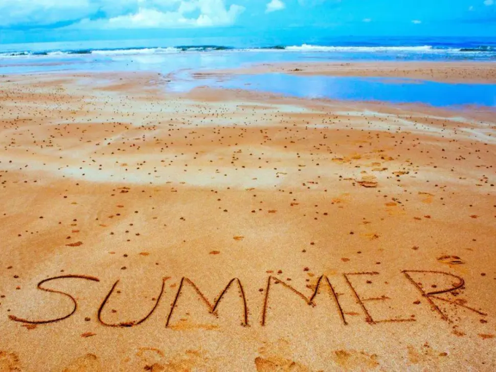 The word summer written in the sand on a beach