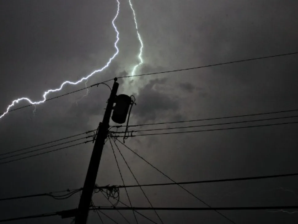 Lightning striking behind a power pole and lines