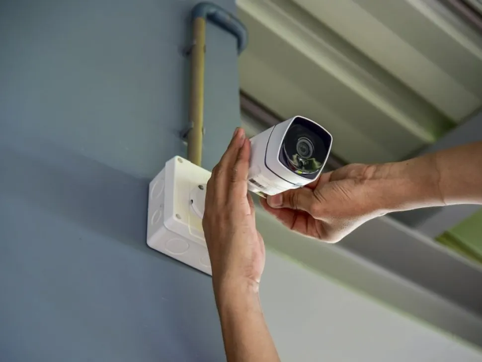 Hands mounting a security camera on an outside wall