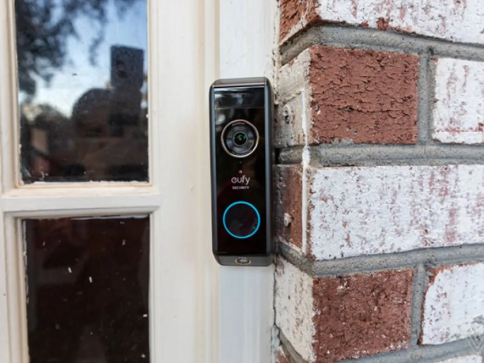 Video doorbell beside a front door on a brick wall