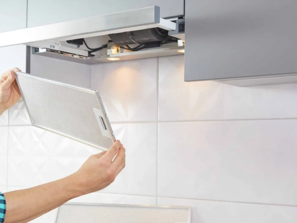Hands removing the filter from a rangehood