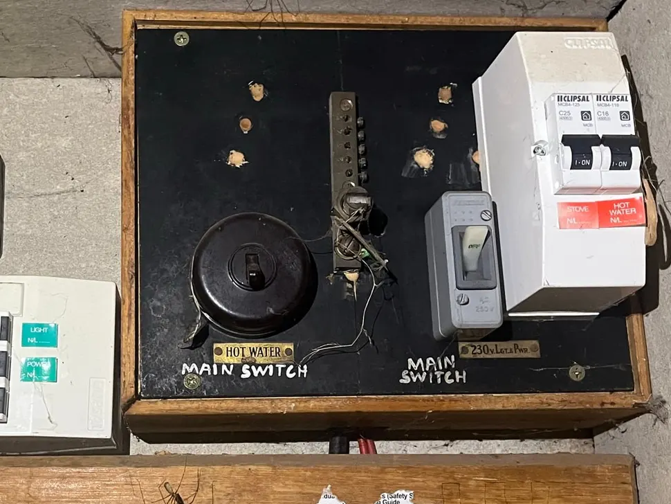 Old switchboard with ceramic fuse holders and aged wiring, before upgrade