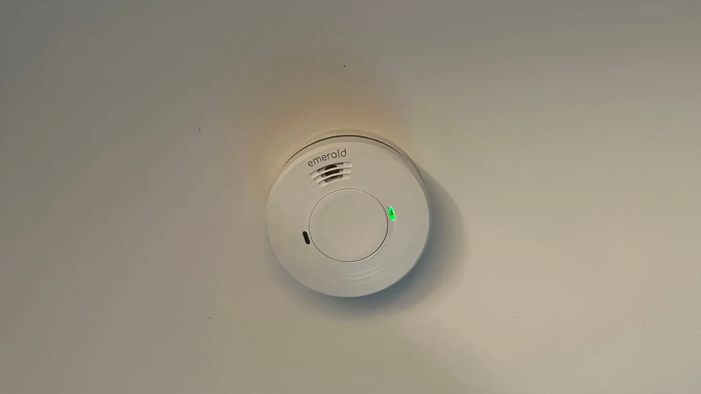 Hardwired smoke alarm fixed to a plain white ceiling