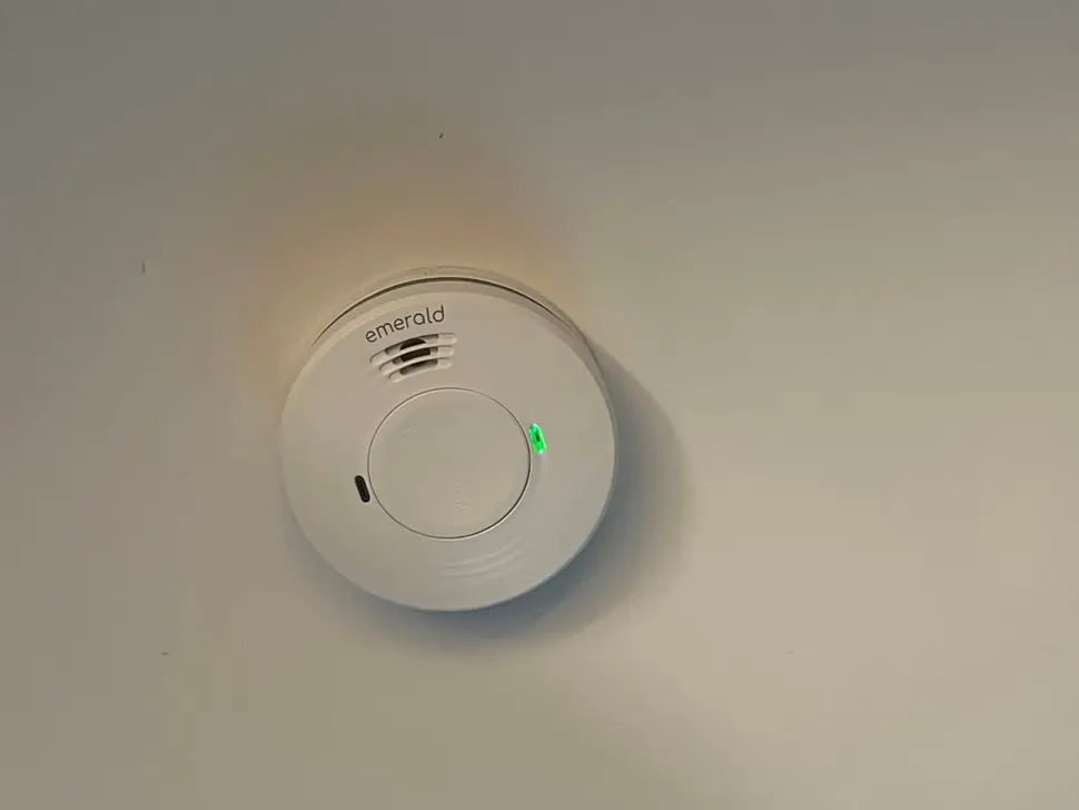 Hardwired smoke alarm fixed to a plain white ceiling