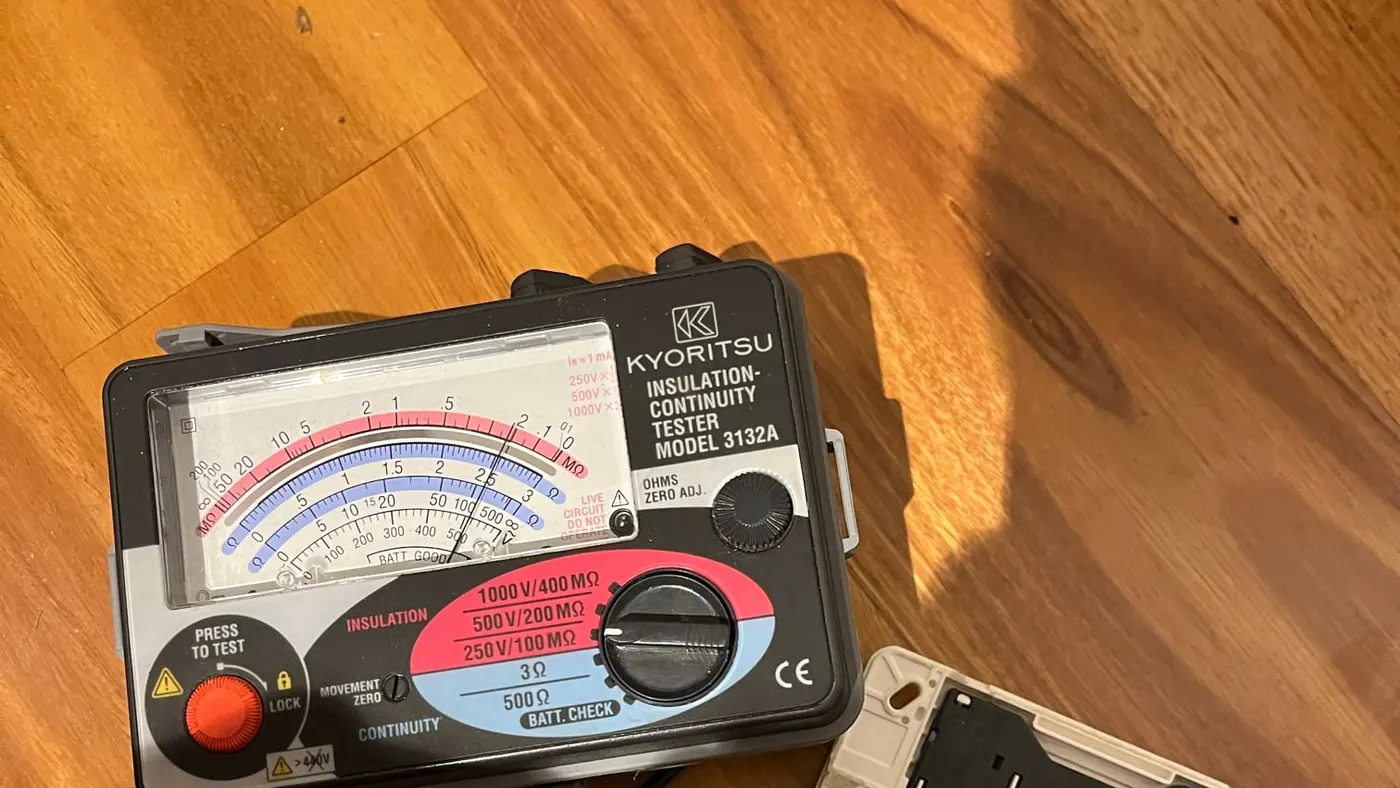 Insulation tester on a timber floor with probes on the back of a power point