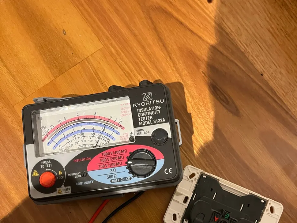 Insulation tester on a timber floor with probes on the back of a power point