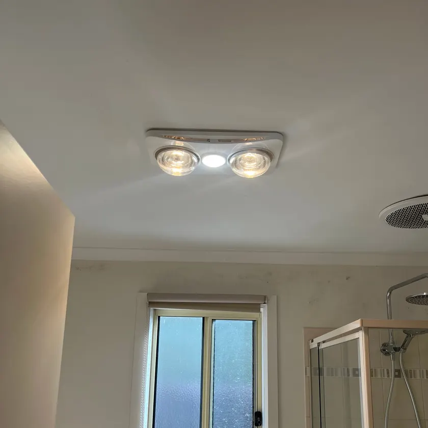 Two-lamp bathroom heater with centre light switched on in a bathroom ceiling