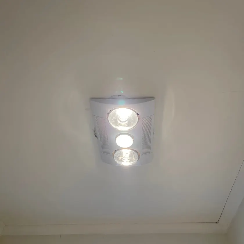 Three-in-one bathroom heater, light and exhaust unit switched on in a ceiling