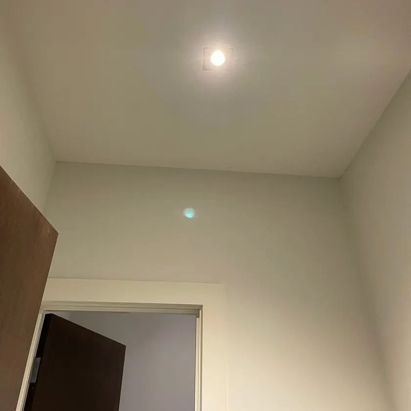 Square recessed downlight lit in a hallway ceiling