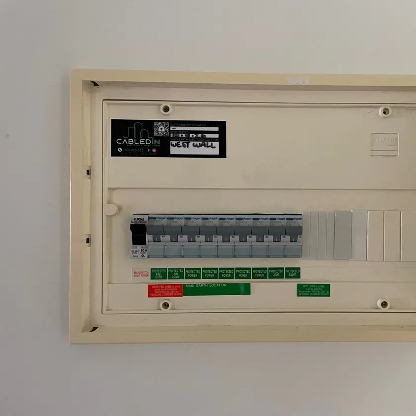 Recessed switchboard with labelled safety switches and a CabledIN sticker recording the date the safety switches were tested