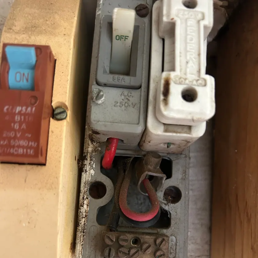 Close view of an old ceramic fuse holder and switch with aged, dusty wiring exposed beneath