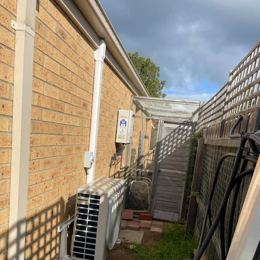 Outdoor split system unit on a brick side wall with conduit and an isolator