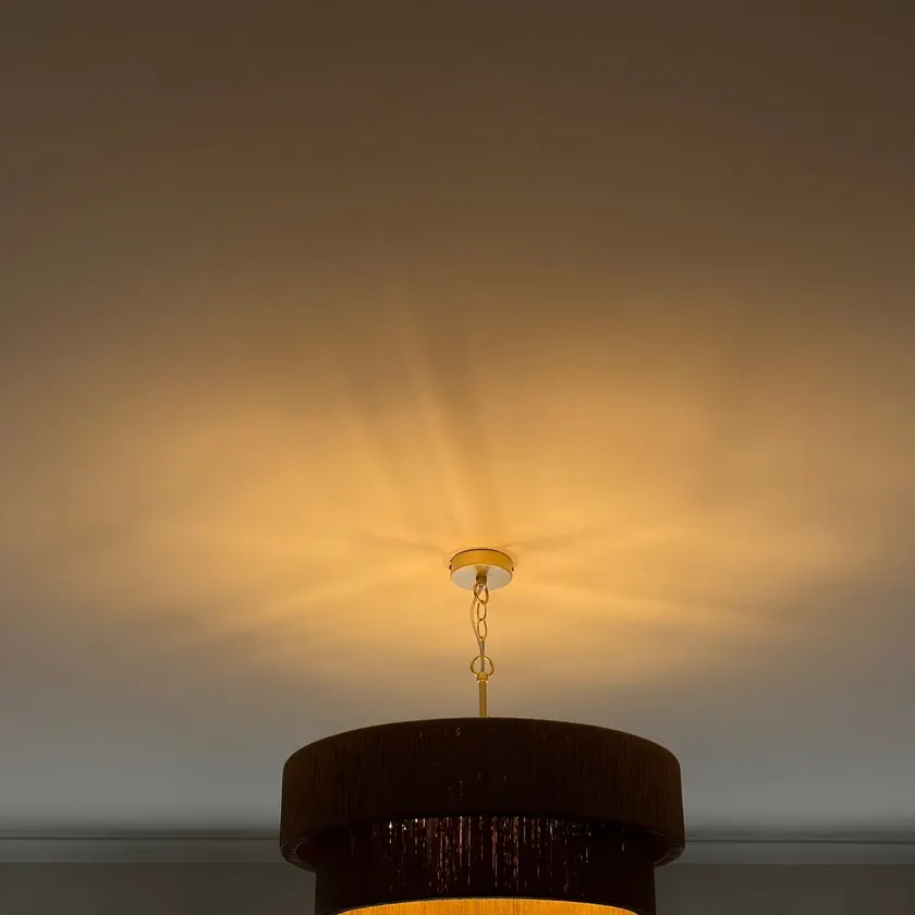 Round two-tier pendant light, lit, hanging from a white ceiling