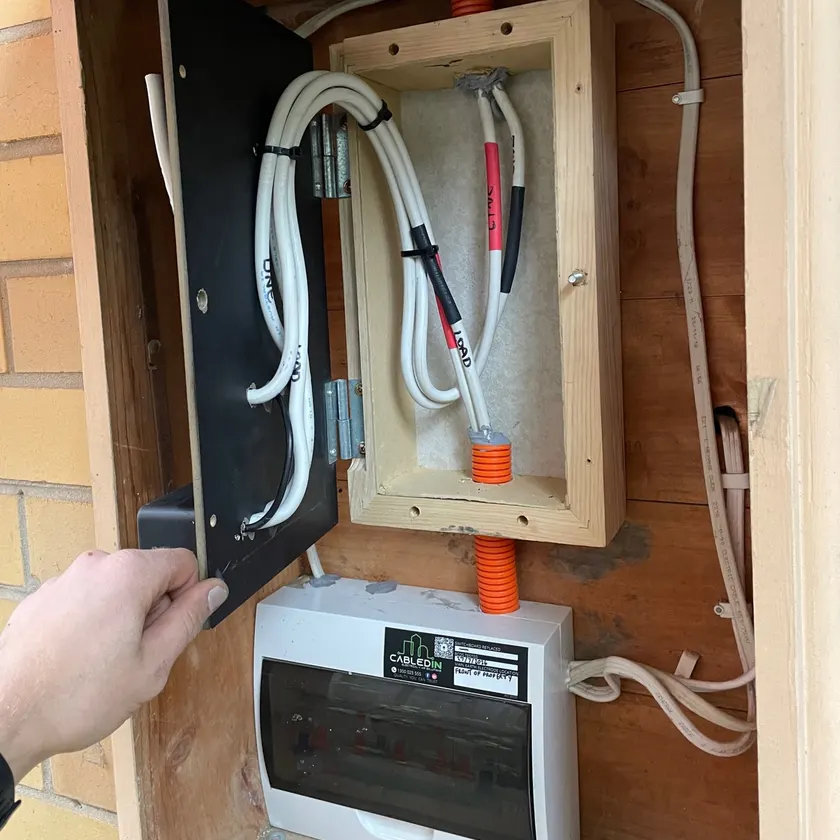 New CabledIN switchboard in a timber enclosure with a hand holding the hinged panel