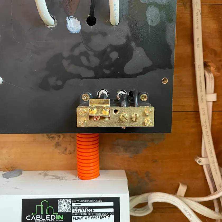 Brass earth bar with a CabledIN sticker beside neatly terminated earth conductors