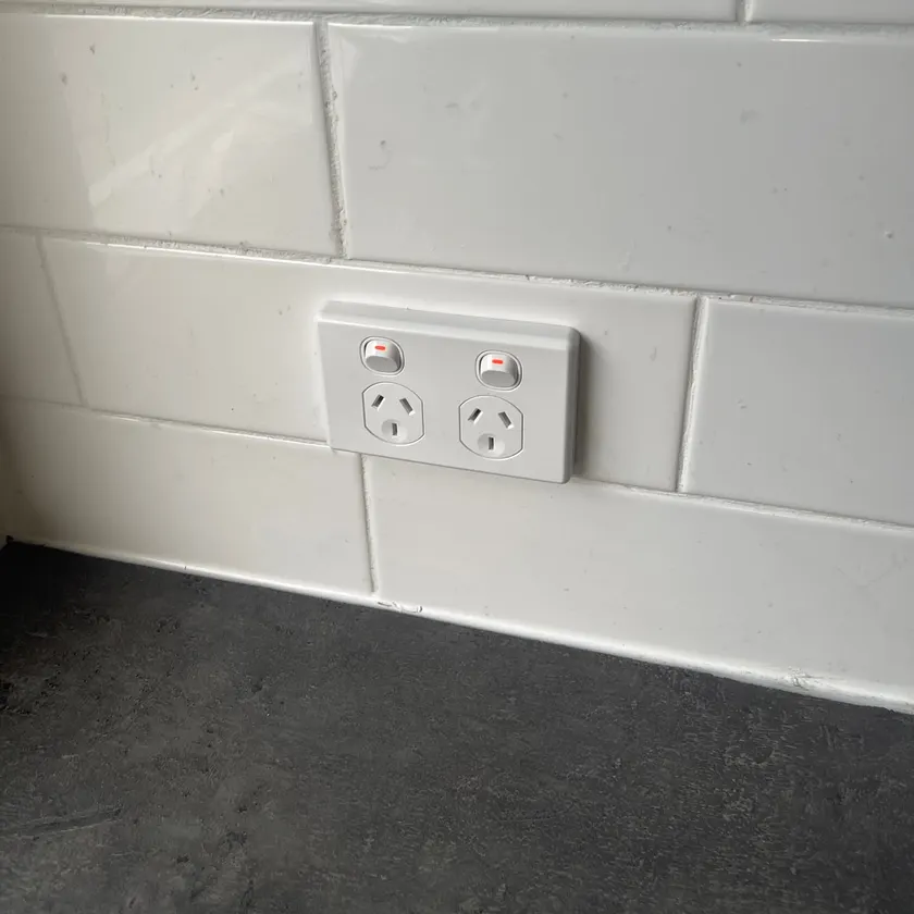 White double power point with switches fitted flush into a white tiled kitchen splashback