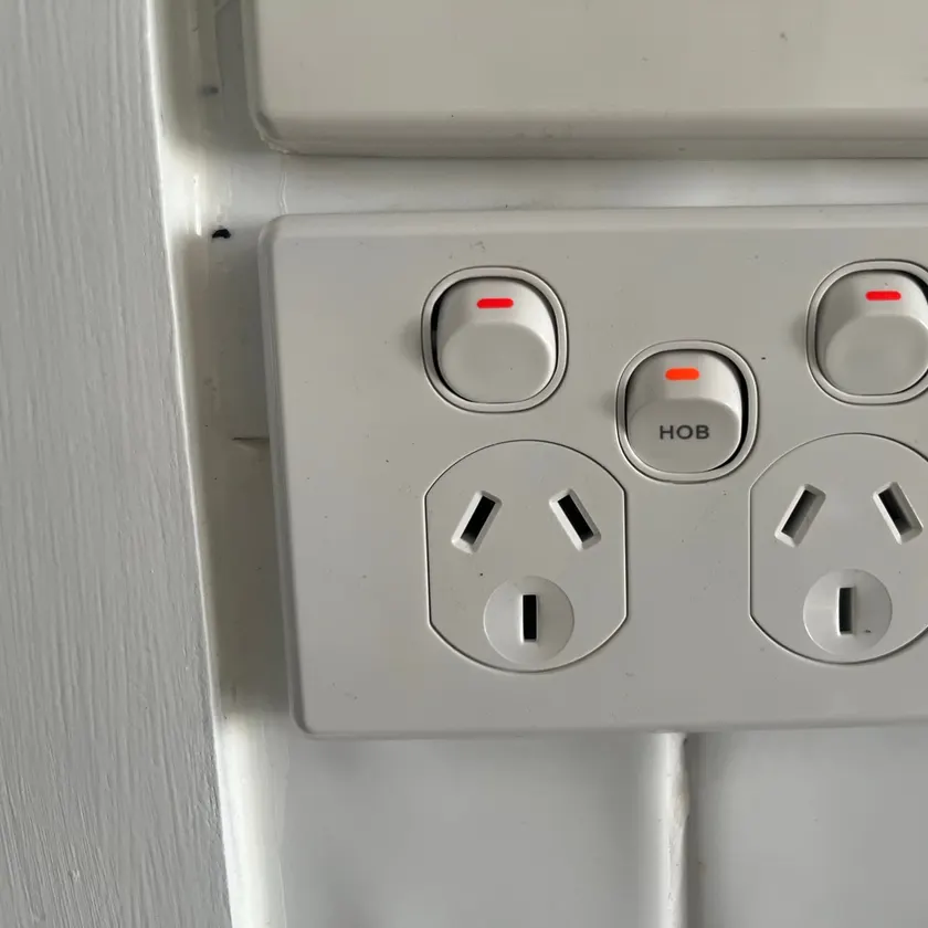 Double power point with a separate switch marked HOB on a white tiled wall
