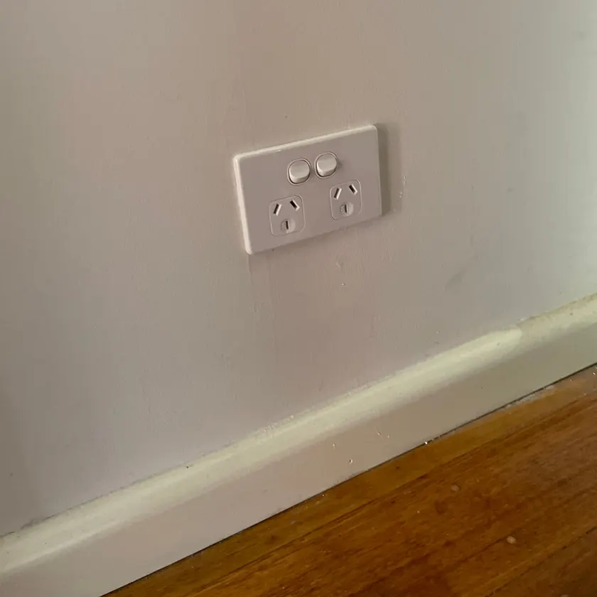 White double power point on a painted wall above a skirting board