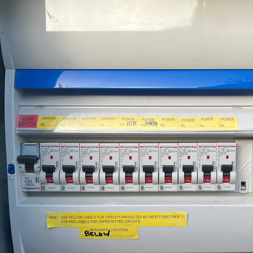 Switchboard with a row of labelled Legrand circuit breakers under a blue trim bar