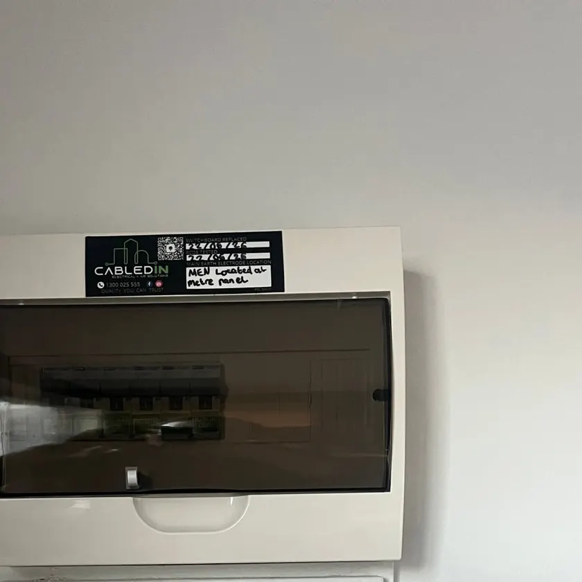 New white switchboard enclosure with smoked cover and a CabledIN sticker on a painted wall