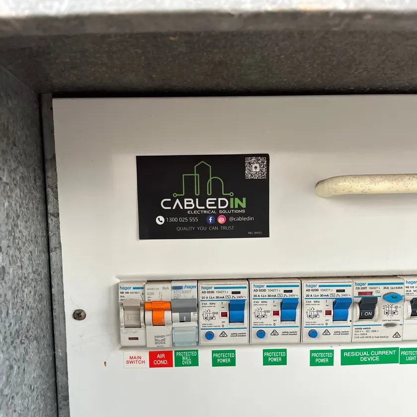 Close-up of a switchboard with CabledIN sticker and labelled Hager safety switches