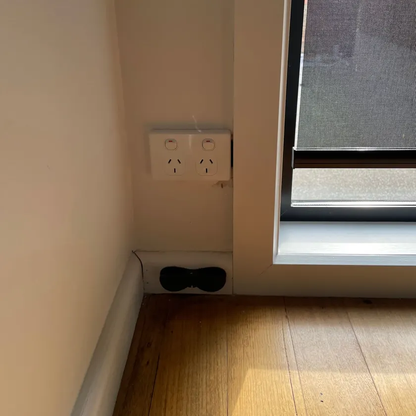 White double power point on a wall beside a window frame