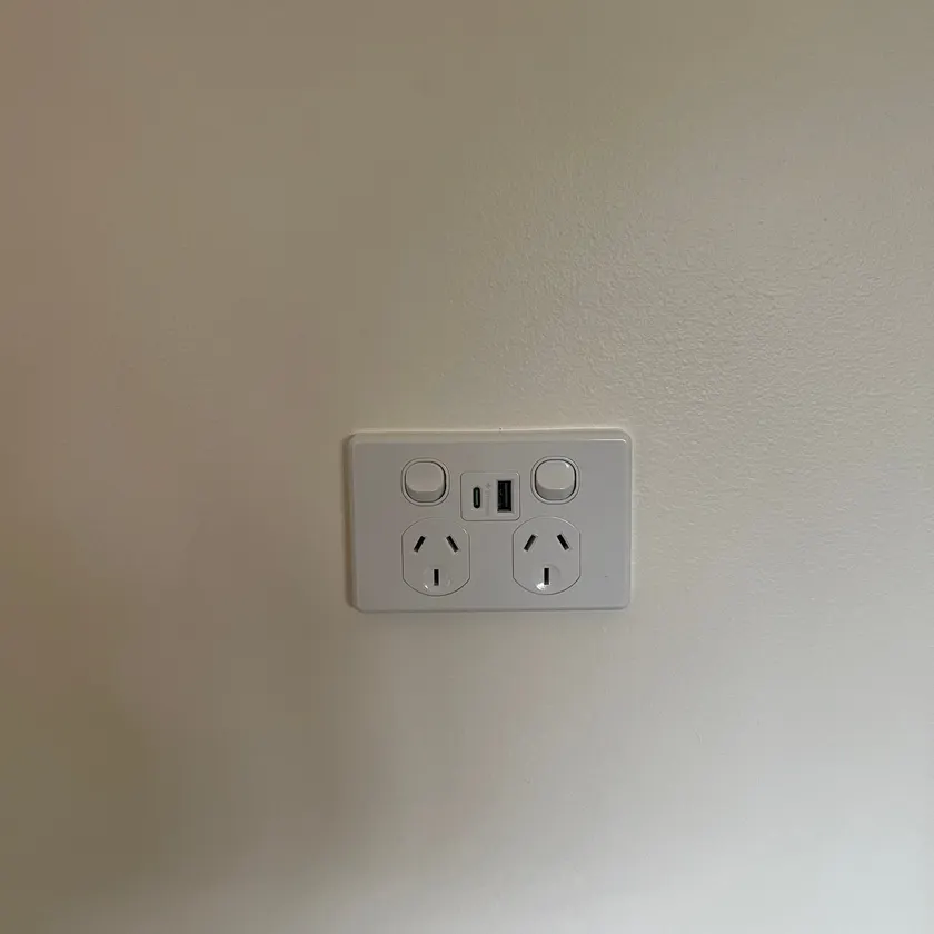 White double power point with USB-A and USB-C ports on a plain painted wall