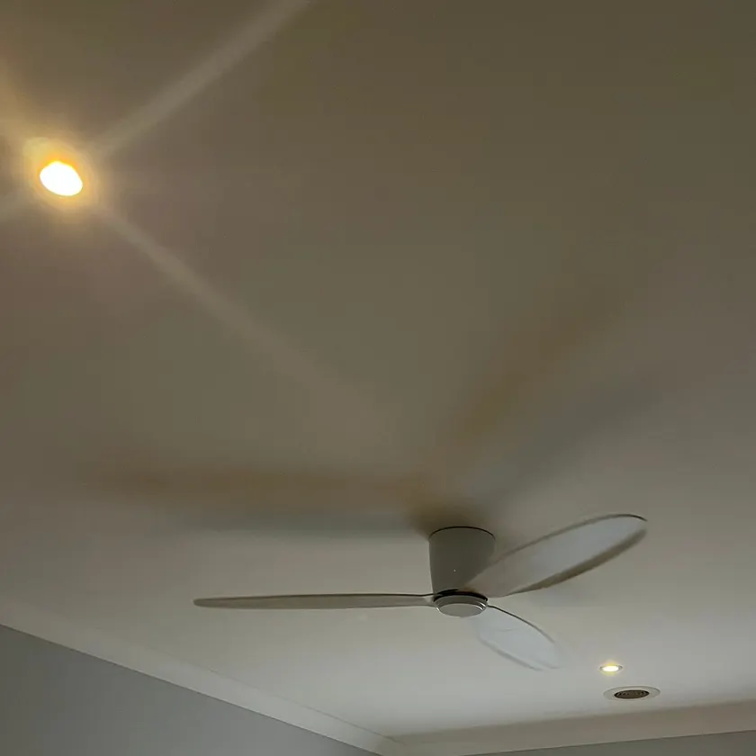 White three-blade ceiling fan on a bedroom ceiling with recessed downlights nearby