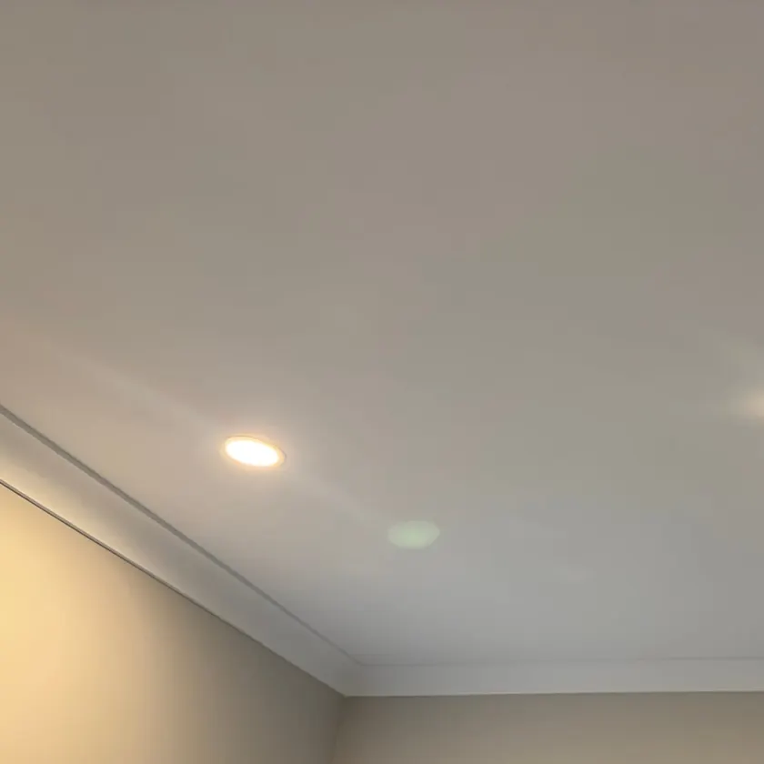 Two lit recessed LED downlights and a fan grille on a white bathroom ceiling