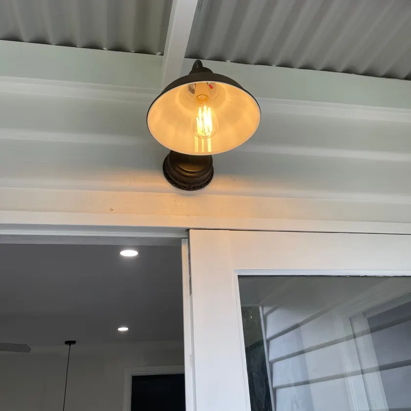 Lit black-shade outdoor wall light fitting on an exterior wall