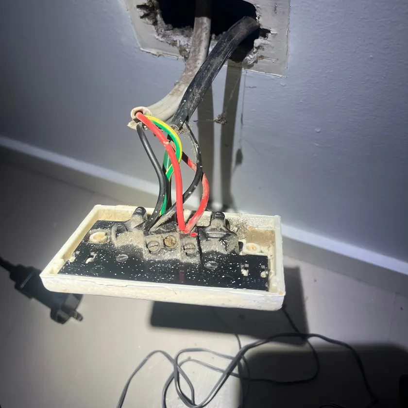 Old double power point pulled off the wall with its dusty wiring exposed