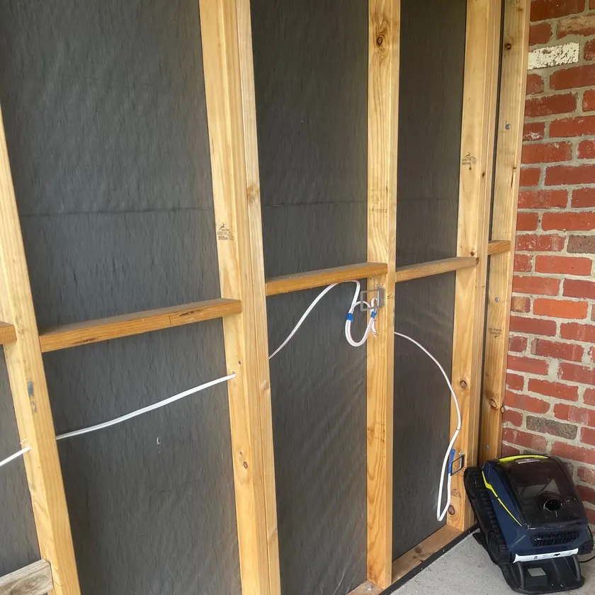 New cable run through a timber wall frame to a power point mounting bracket beside a brick wall