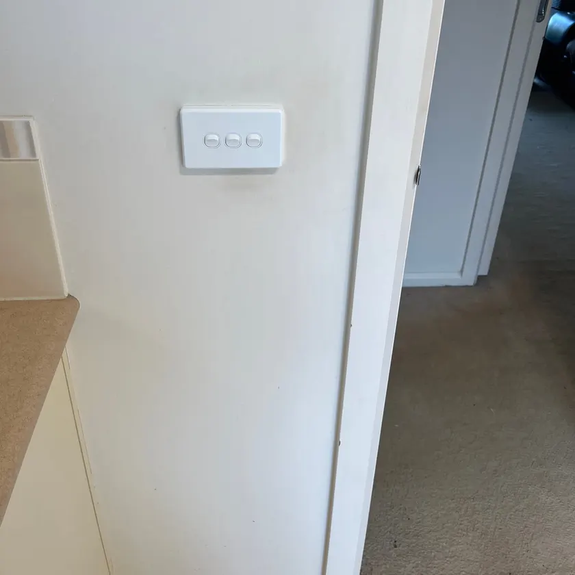 New white three-gang light switch plate mounted on an interior wall