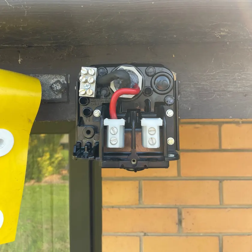 New service fuse holder with its cover off, fixed to a timber fascia above brickwork