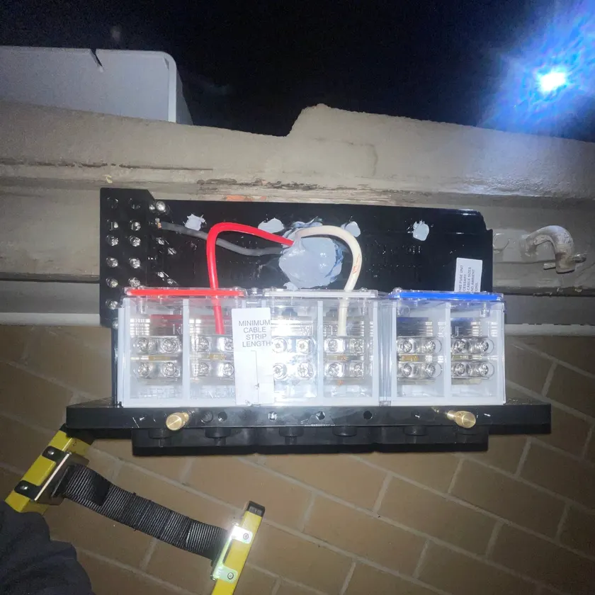 New three-phase service fuse unit on a fascia at night, clear covers showing the terminals