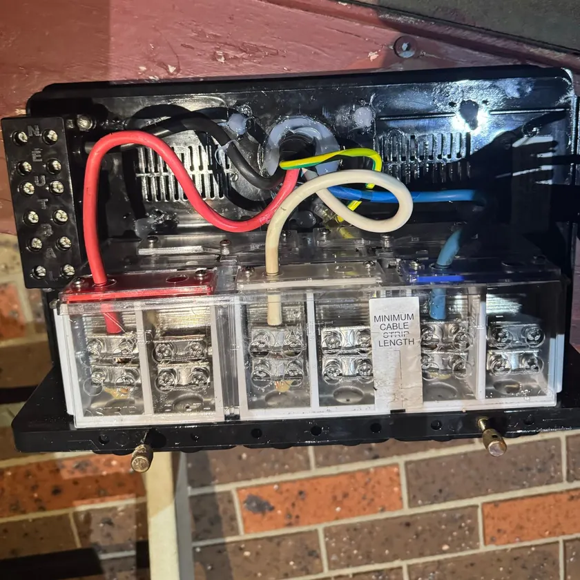 Close-up of a three-phase service fuse unit wired with red, white and blue cables at night