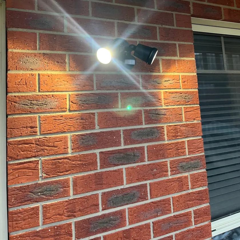 Twin-head sensor spotlight mounted on an exterior brick wall