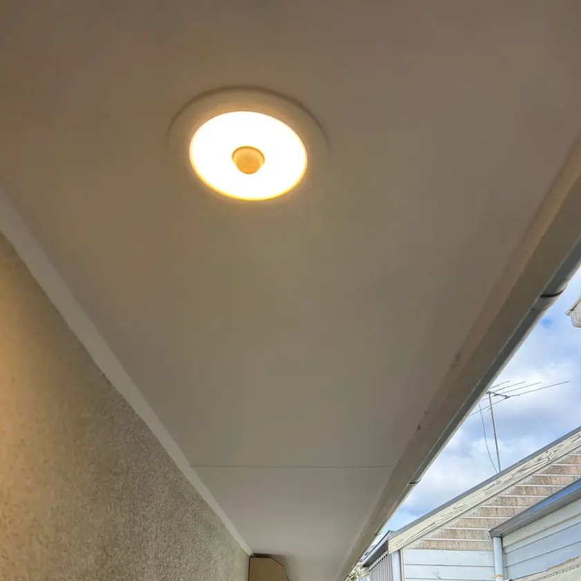 Round sensor light mounted under the eave of a house