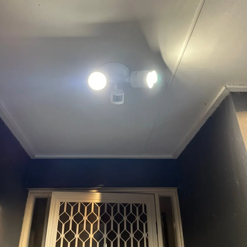 White twin-head sensor spotlight mounted on a porch ceiling