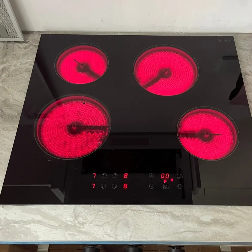 Black touch-control ceramic cooktop with four elements glowing red on a stone-look benchtop