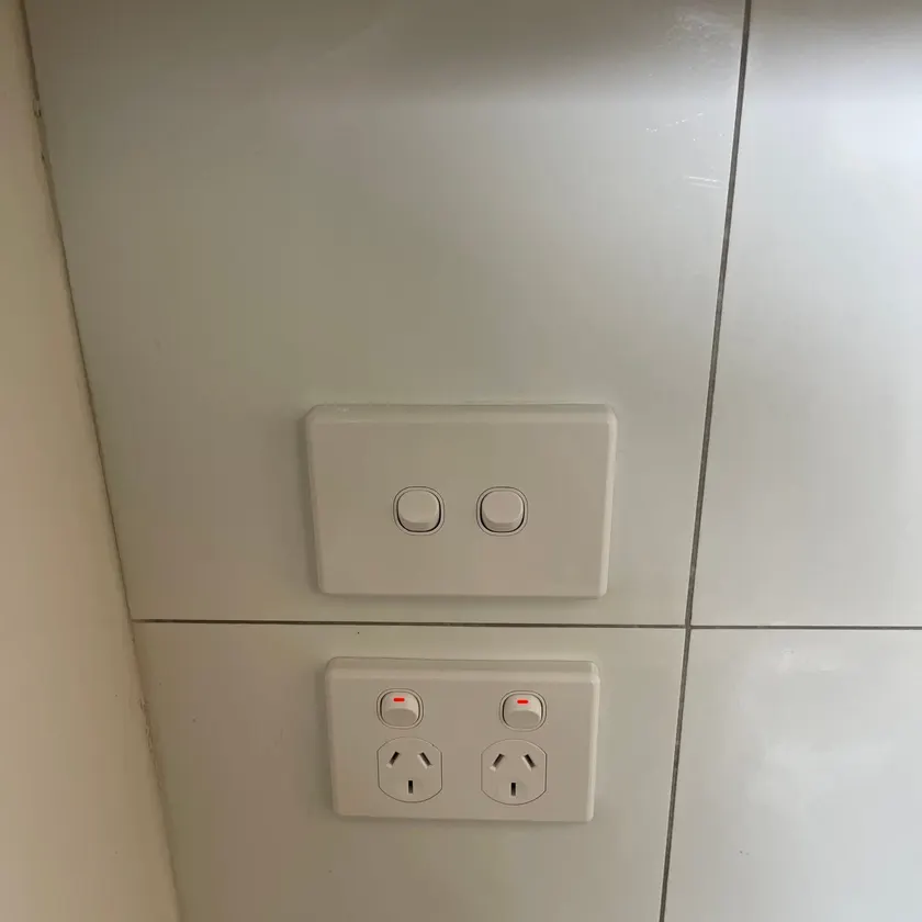 New white double power point and two-gang switch on a white tiled kitchen splashback