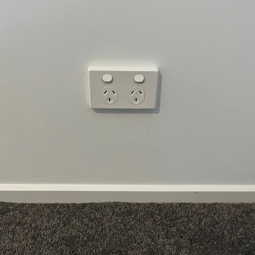 New white double power point fitted level on a plain painted wall above skirting and carpet