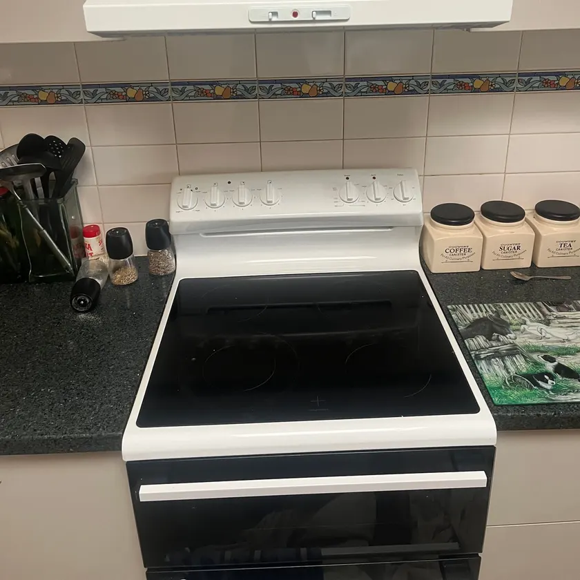 White fixed rangehood mounted under cupboards above a white freestanding electric stove