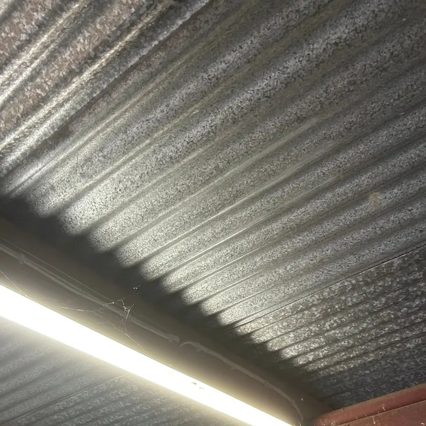 LED batten and surface conduit under the metal roof of a garage