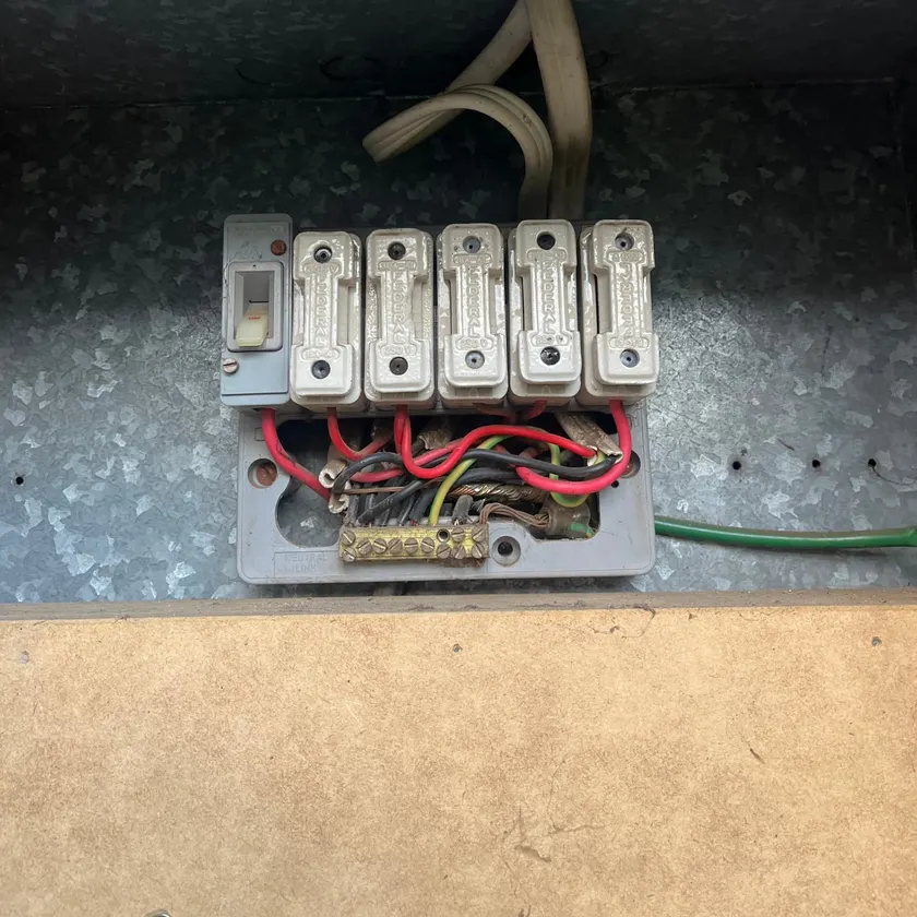 Old switchboard with a row of ceramic rewirable fuses in a metal enclosure